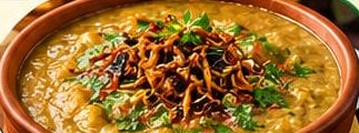 Bowl of chicken haleem with fried onions and coriander
